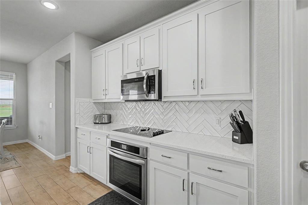 185 Chester Road Springtown, TX 76082 - Photo 19 of 40 Bright kitchen featuring white shaker cabinetry, stainless steel microwave, and an integrated oven