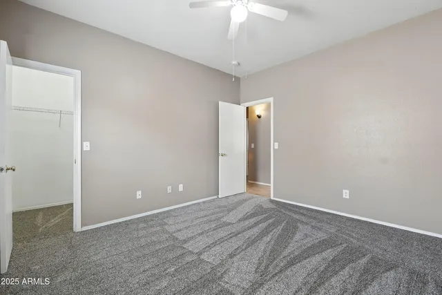 a view of an empty room with a chandelier fan