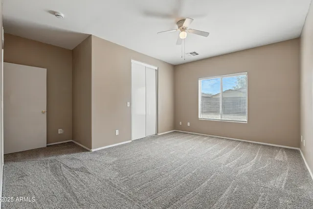an empty room with windows and fan