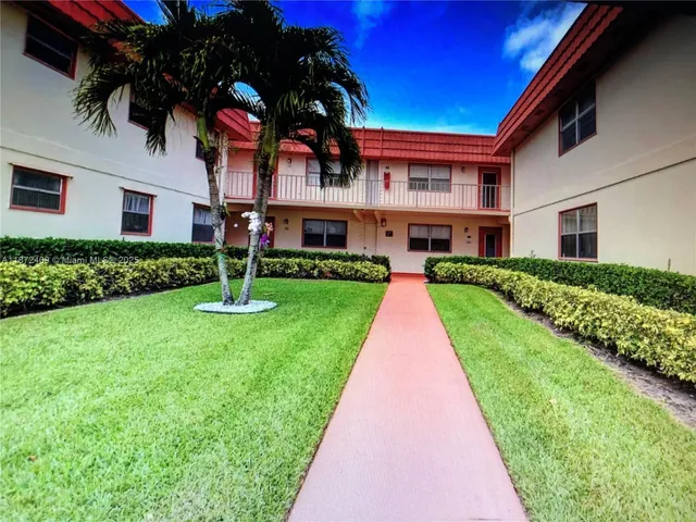 a view of a white house with a big yard and potted plants