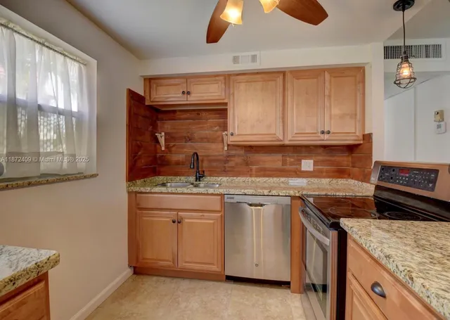 a kitchen with granite countertop a sink stainless steel appliances and cabinets