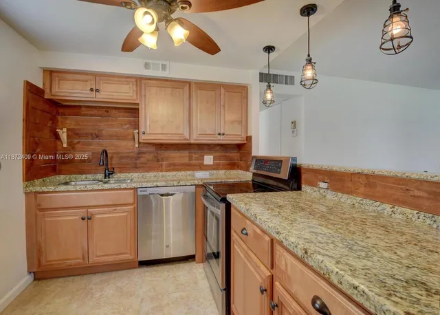 a kitchen with granite countertop cabinets stainless steel appliances a sink and a counter top space