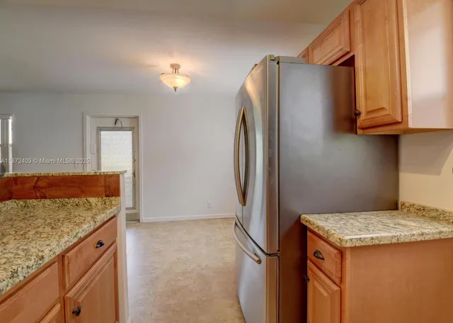 a kitchen with granite countertop a refrigerator and a sink