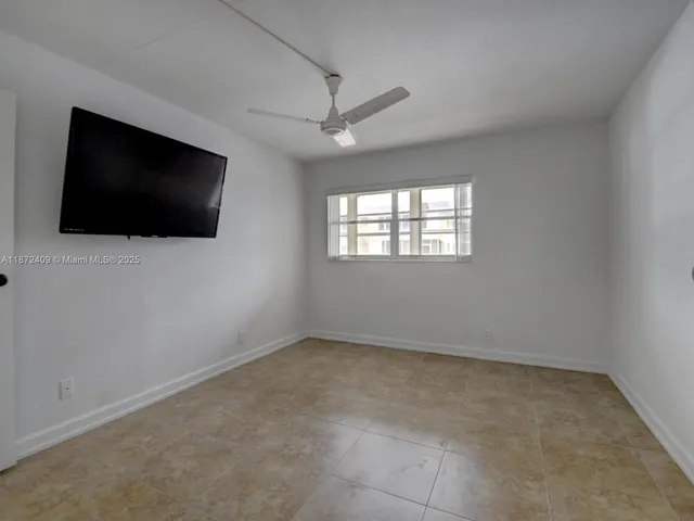 an empty room with windows tv and fan