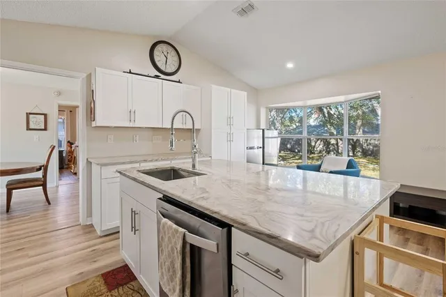a kitchen with granite countertop a stove a sink a counter space and cabinets