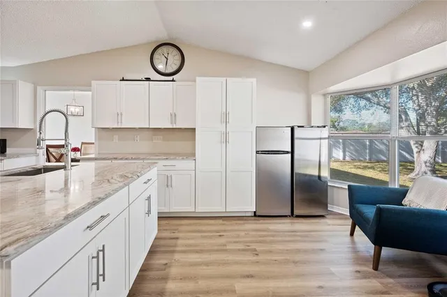 a kitchen with stainless steel appliances granite countertop a refrigerator a stove and white cabinets with wooden floor