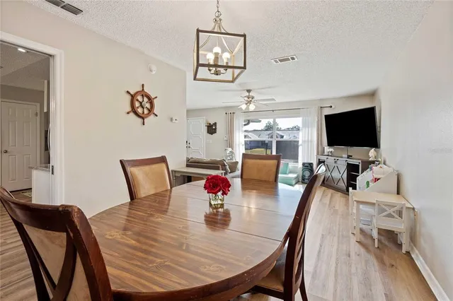 a view of a dining room with furniture a chandelier and wooden floor