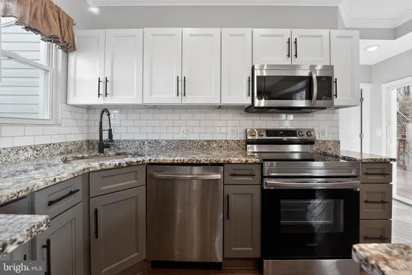 a kitchen with stainless steel appliances granite countertop a stove a microwave and a sink