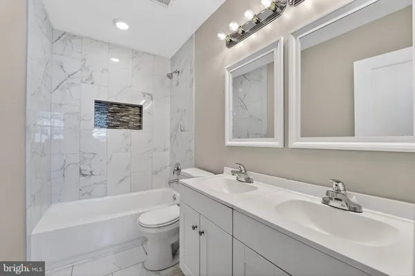 a bathroom with a toilet a sink a mirror a bathtub and shower