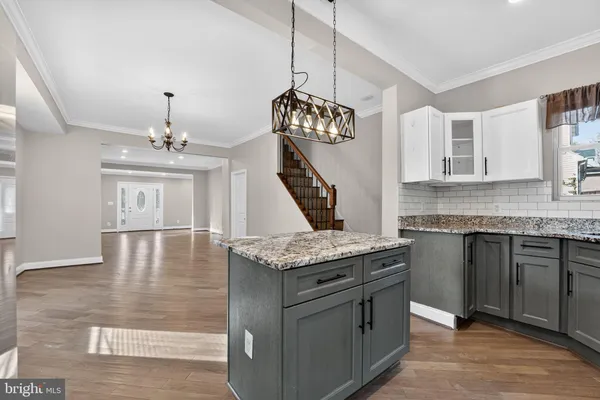 a kitchen with stainless steel appliances granite countertop a stove a sink dishwasher and white cabinets with wooden floor