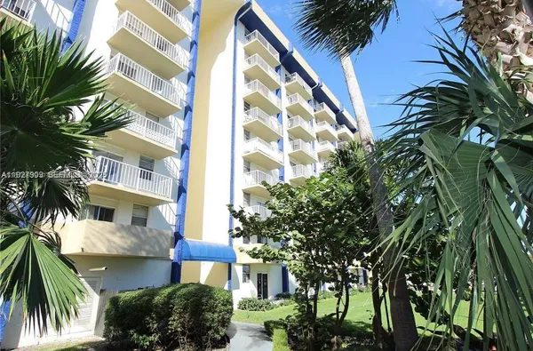 a front view of multi story residential apartment building with a yard and potted plants