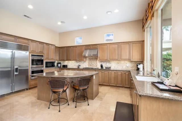 a kitchen with kitchen island granite countertop wooden cabinets and stainless steel appliances