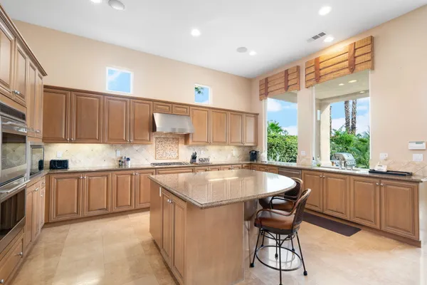 a kitchen with stainless steel appliances granite countertop table chairs sink and cabinets