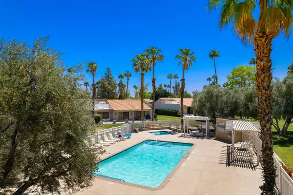 a view of a swimming pool with a yard and palm trees