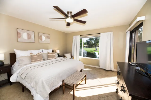 a spacious bedroom with a bed and a flat screen tv