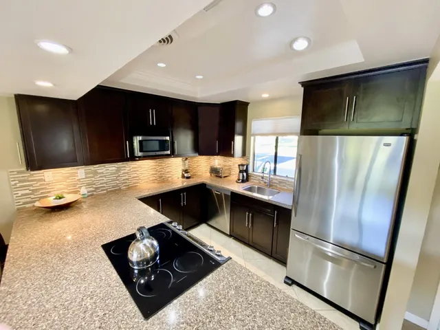 a kitchen with stainless steel appliances granite countertop a refrigerator and a sink