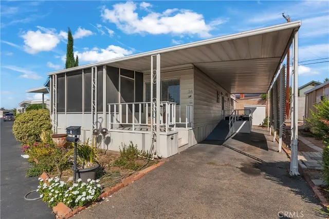 a view of a house with a wooden bench next to a yard