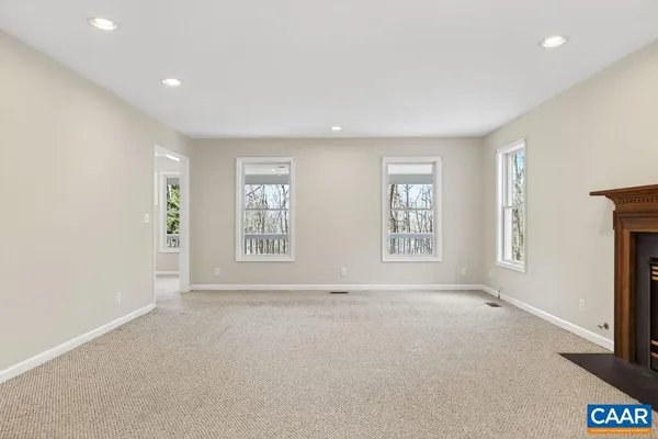 an empty room with windows and fireplace