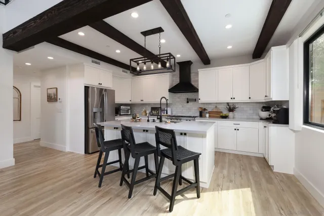 a kitchen with stainless steel appliances kitchen island granite countertop a table chairs refrigerator and microwave