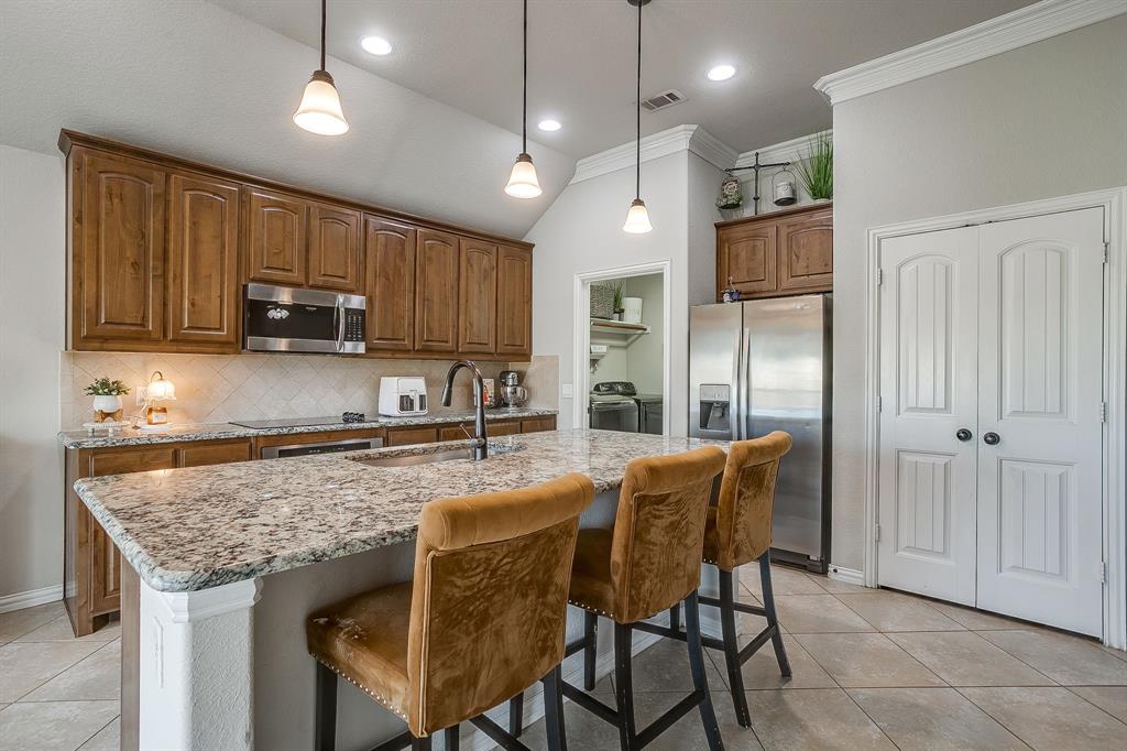 8005 Canyon Ridge Drive Godley, TX 76044 - Photo 12 of 40 a kitchen with granite countertop wooden cabinets a center island and stainless steel appliances