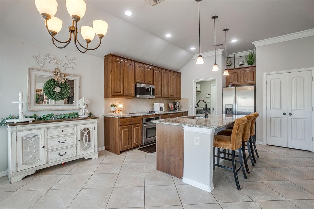 8005 Canyon Ridge Drive Godley, TX 76044 - Photo 13 of 40 a kitchen with stainless steel appliances granite countertop a stove top oven a sink dishwasher a dining table and chairs with wooden floor