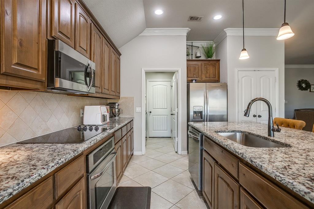 8005 Canyon Ridge Drive Godley, TX 76044 - Photo 15 of 40 a kitchen with kitchen island granite countertop a sink stainless steel appliances and cabinets