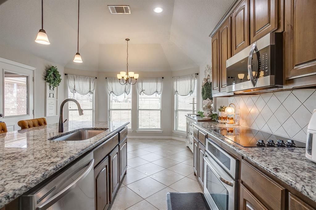 8005 Canyon Ridge Drive Godley, TX 76044 - Photo 16 of 40 a kitchen with stainless steel appliances granite countertop a sink a stove and a wooden cabinets
