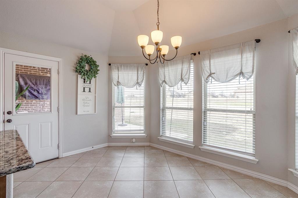 8005 Canyon Ridge Drive Godley, TX 76044 - Photo 19 of 40 a view of an empty room with a chandelier fan and kitchen view