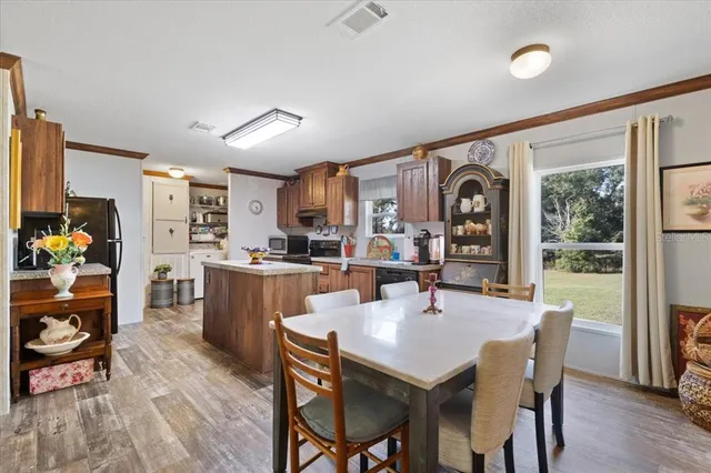 a kitchen with stainless steel appliances granite countertop a refrigerator a sink dishwasher a stove and a dining table with wooden floor