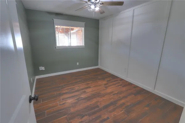 an empty room with wooden floor and windows