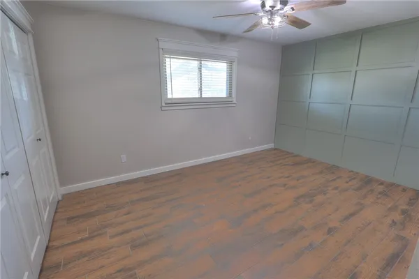 en empty room with wooden floor and fan