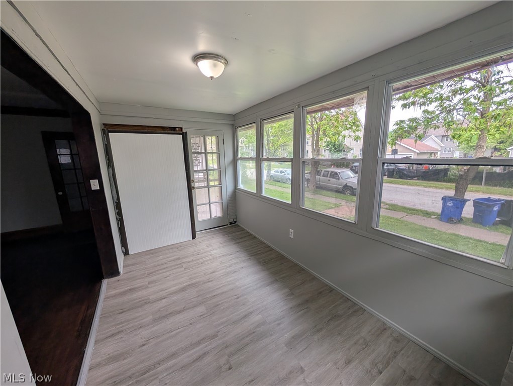 475 East 146th Street Cleveland, OH 44110 - Photo 7 of 28 Sunroom featuring light wood-finish flooring, multiple windows, a ceiling-mounted light fixture, and a glass-paned door