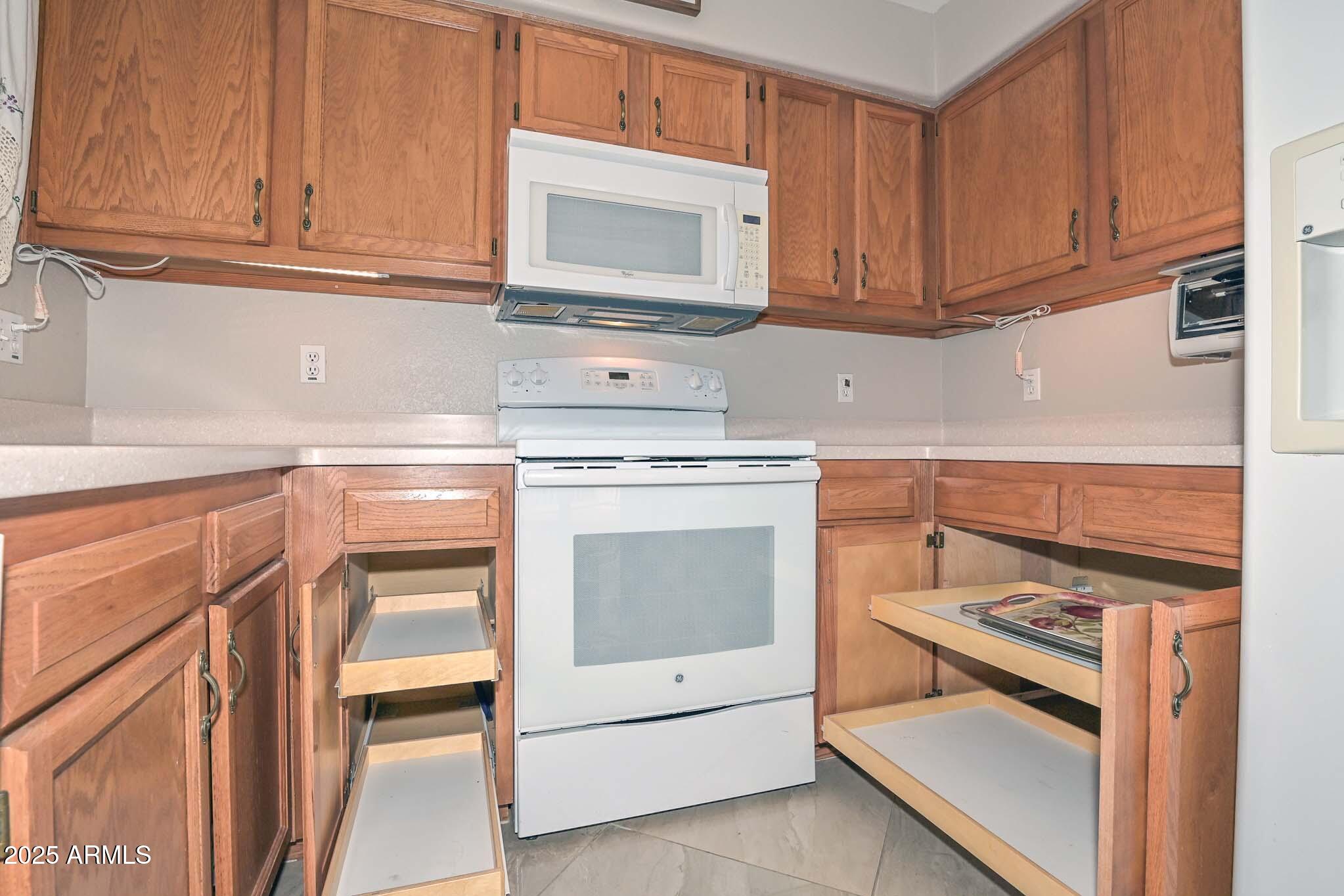 9151 West Greenway Road, Unit 113 Peoria, AZ 85381 - Photo 11 of 36 a kitchen with granite countertop white cabinets and white appliances