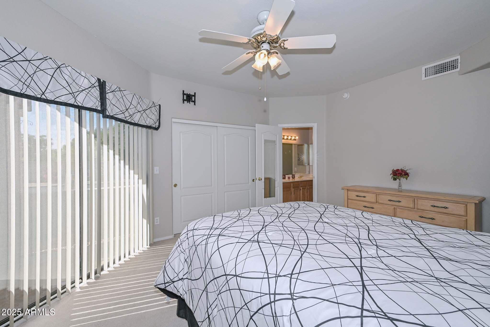 9151 West Greenway Road, Unit 113 Peoria, AZ 85381 - Photo 17 of 36 a bedroom with a large bed and a chandelier