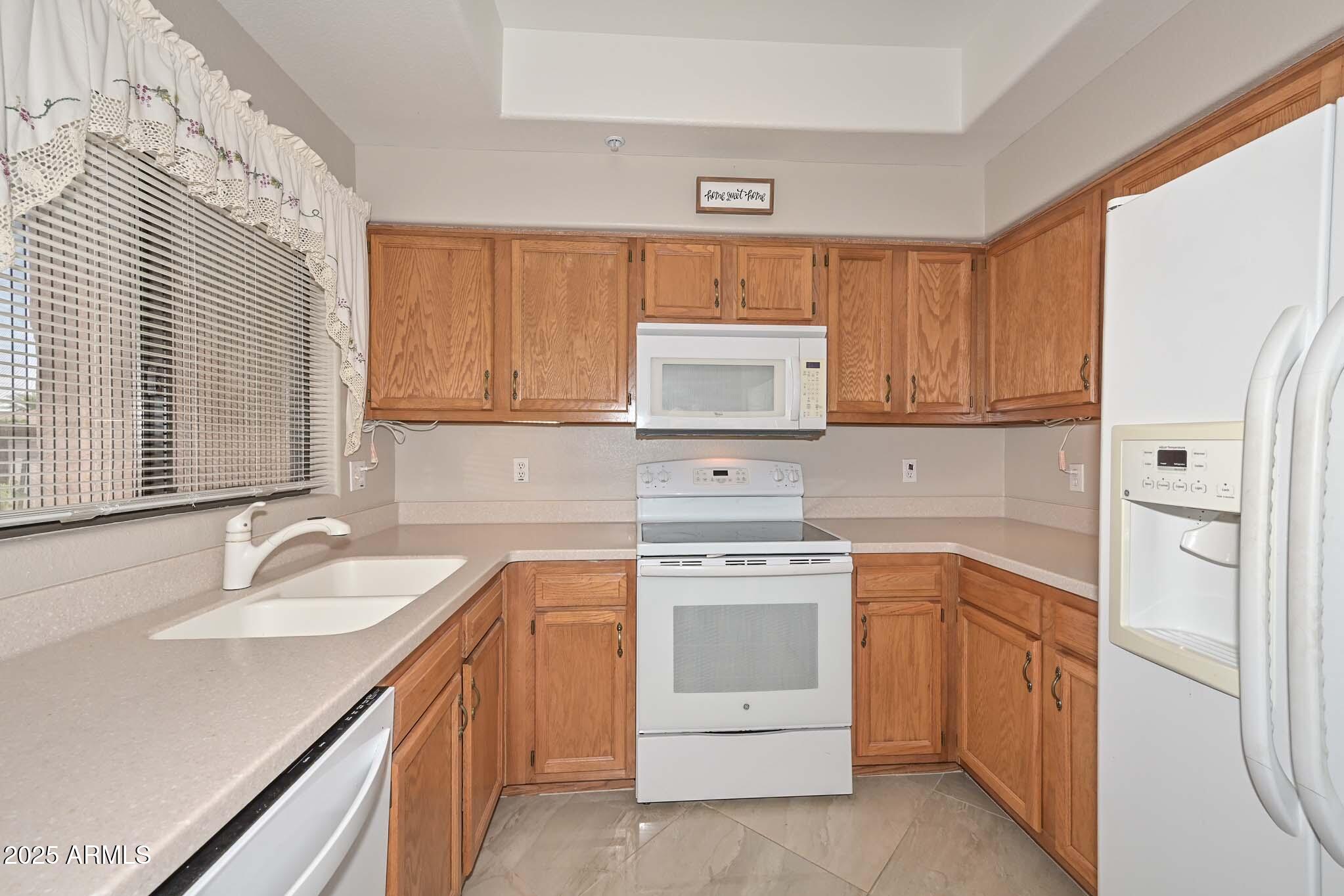 9151 West Greenway Road, Unit 113 Peoria, AZ 85381 - Photo 9 of 36 a kitchen with white cabinets sink and stove