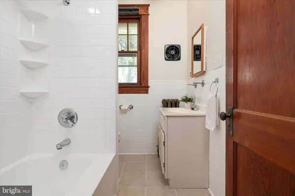 a white bath tub sitting next to a white sink and vanity