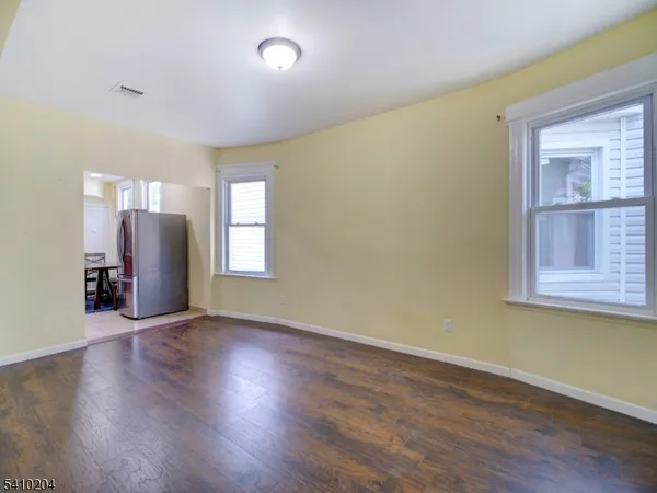 a view of an empty room with window and wooden floor