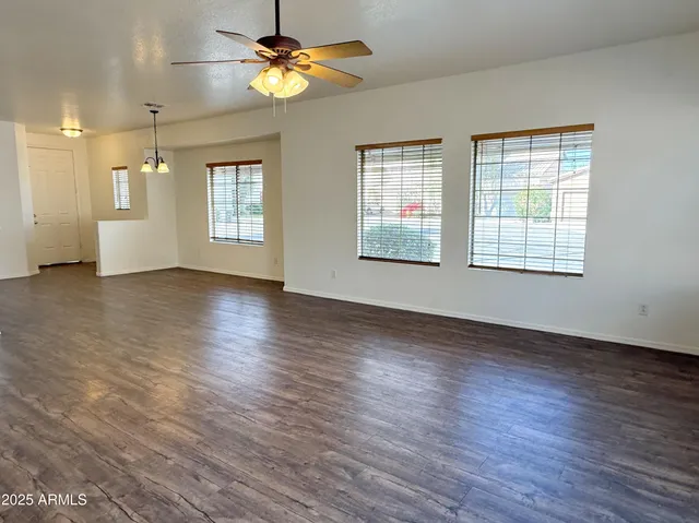 a view of an empty room with a window and wooden floor