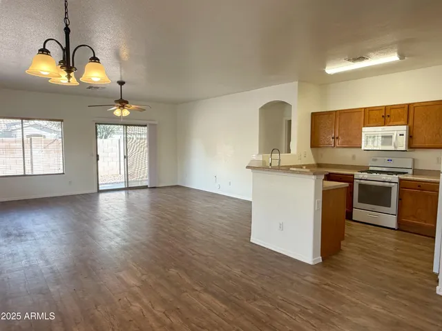 a kitchen with stainless steel appliances granite countertop a stove a sink dishwasher and white cabinets with wooden floor