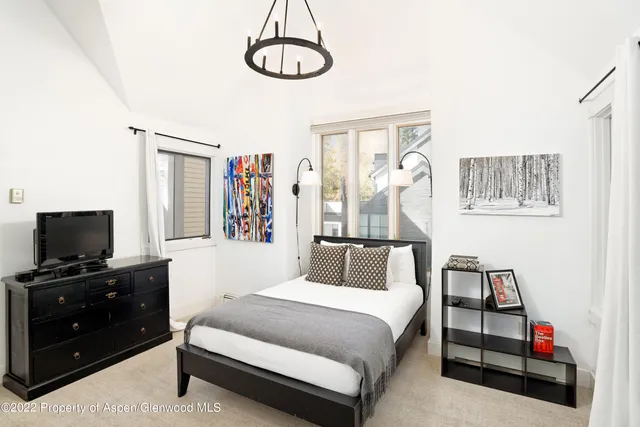 a bedroom with a bed and a flat tv screen on the dresser