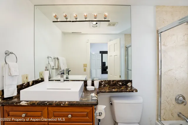 a bathroom with a granite countertop sink a toilet and a mirror