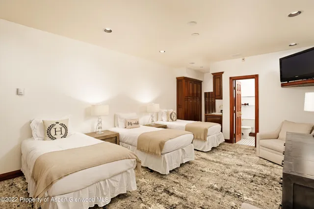 a spacious bedroom with two beds and a flat screen tv