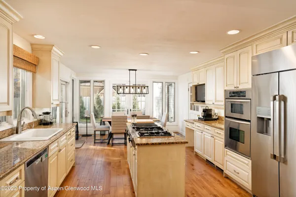 a kitchen with stainless steel appliances a refrigerator a stove a sink dishwasher and white cabinets with wooden floor