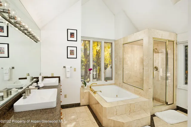 a bathroom with a tub a sink and a large mirror