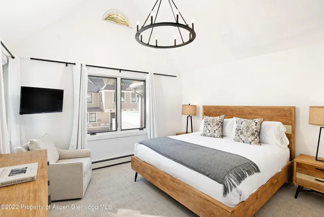 a spacious bedroom with a bed and a flat screen tv