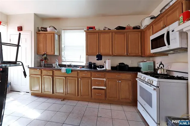 a kitchen with stainless steel appliances granite countertop a stove top oven a sink a microwave and cabinets