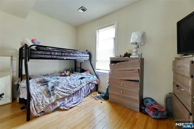 a bedroom with a bed and a flat tv screen on dresser