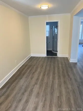 a view of an empty room with wooden floor and closet