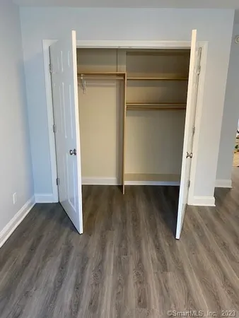 a view of an empty room with wooden floor and closet