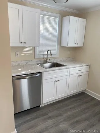 a kitchen with stainless steel appliances granite countertop a sink a stove and white cabinets with wooden floor